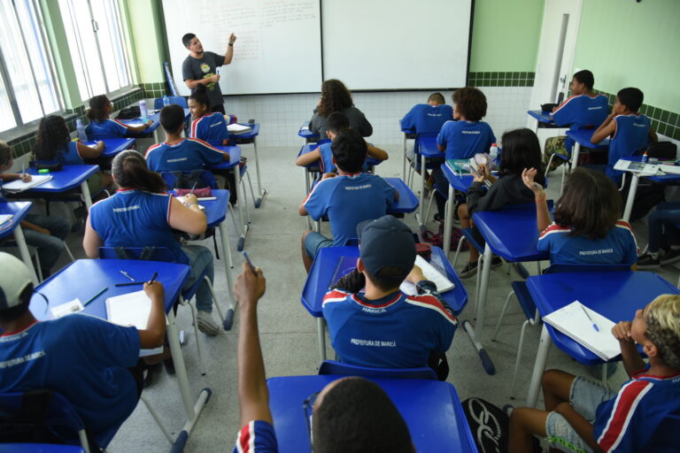 Estudantes em sala de aula com professor, mostrando aprendizado e alfabetização em Maricá, RJ.