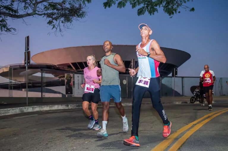 Atletas correndo em evento de rua em Niterói, com a Baía de Guanabara ao fundo, durante a Meia Maratona.