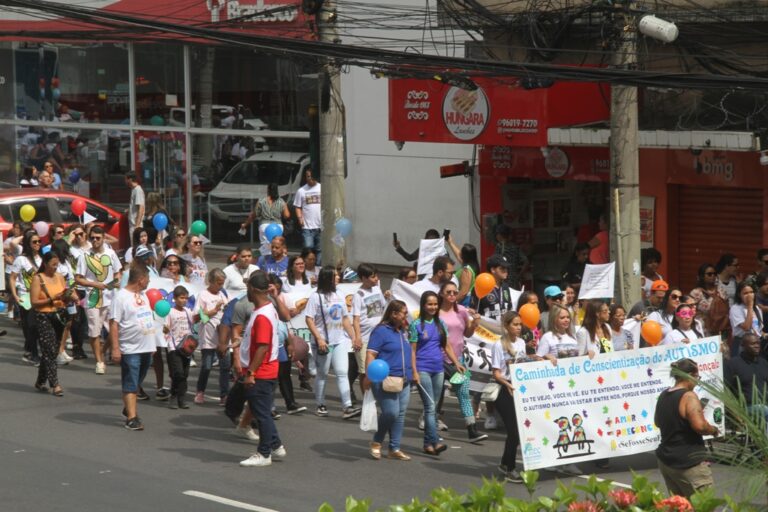 Centenas de pessoas participam da 7ª Caminhada em Conscientização do Autismo no Centro de São Gonçalo, com balões e cartazes.