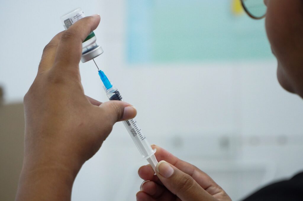 Profissional de saúde aplicando vacina da gripe em São Gonçalo. Campanha de imunização segue na cidade.