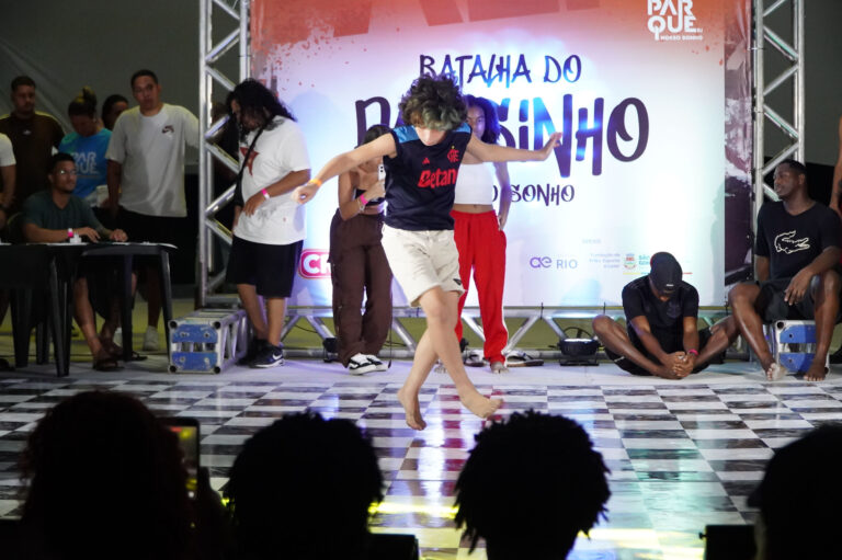 Jovens dançando passinho em palco e crianças brincando em infláveis no Parque RJ Nosso Sonho, São Gonçalo.