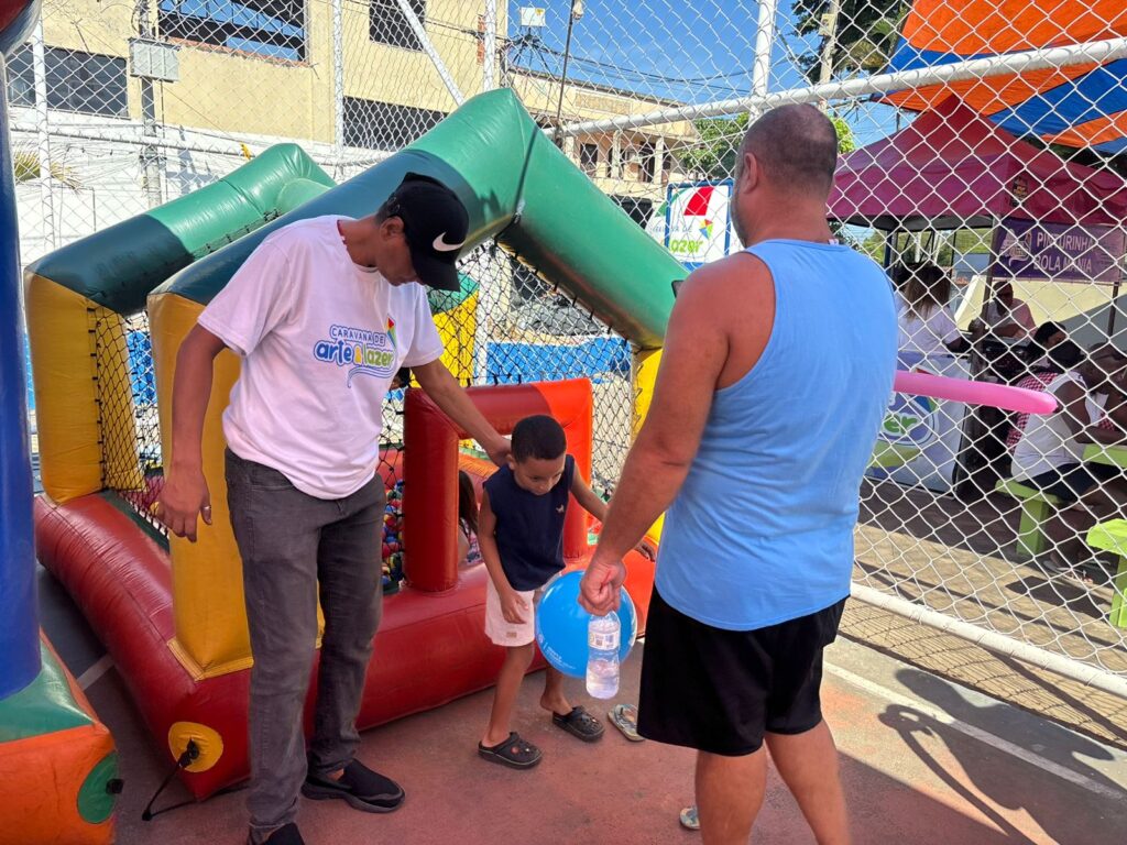 Crianças brincam em evento da Caravana de Arte e Lazer no Mutuá, São Gonçalo, com brinquedos infláveis e atividades.
