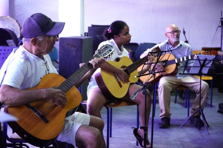 Alunos de diversas idades aprendem a tocar violão durante aula gratuita do projeto CRIA SG em São Gonçalo.