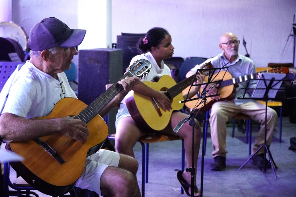 Alunos de diversas idades aprendem a tocar violão durante aula gratuita do projeto CRIA SG em São Gonçalo.