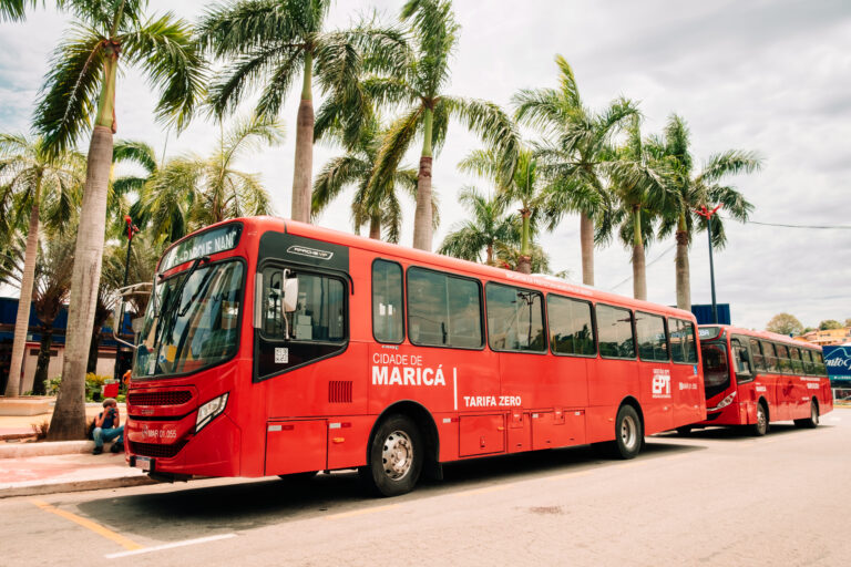 Ônibus Vermelhinho da EPT circulando em Maricá, com pessoas ao redor, simbolizando o transporte público gratuito.