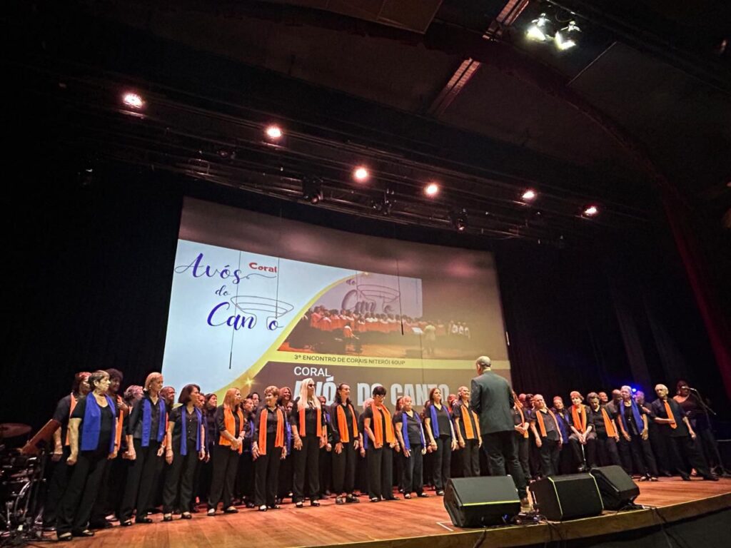 Corais se apresentando em palco iluminado, com cantores em diferentes formações e trajes, celebrando a música.