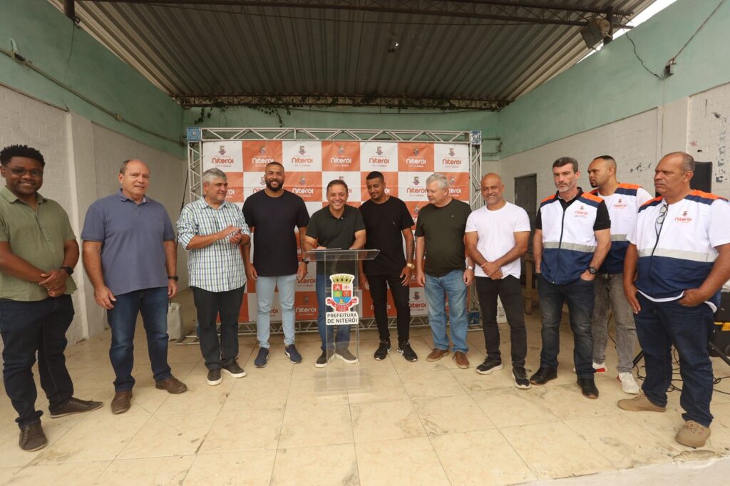 Parque de energia solar no Morro do Boa Vista, Niterói, com painéis fotovoltaicos e vegetação em área de comunidade.