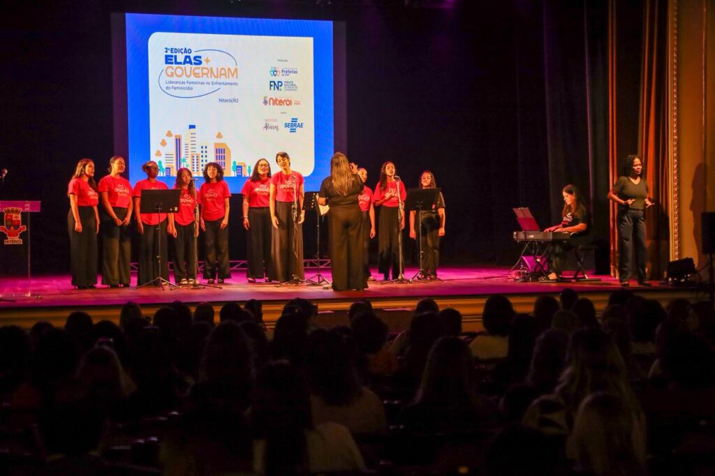 Prefeito, primeira-dama e outras autoridades femininas no palco do Theatro Municipal durante o evento "Elas Governam" em Niterói.