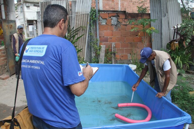 Agente de saúde em São Gonçalo vistoria quintal em busca de focos do mosquito Aedes aegypti, vetor da dengue.