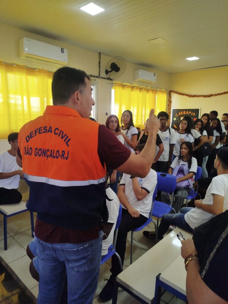 Agentes da Defesa Civil de São Gonçalo palestram para estudantes em sala de aula sobre prevenção de riscos.