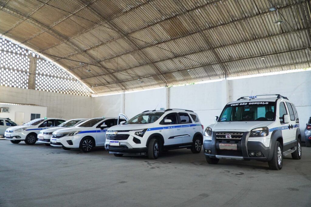 Taxista mostrando documentos e veículo durante vistoria de táxi em São Gonçalo para licença de 2026