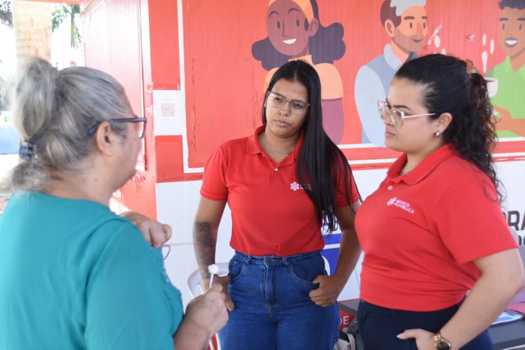 Atendimento itinerante do Banco Mumbuca em Inoã, Maricá, com van e equipe orientando moradores.