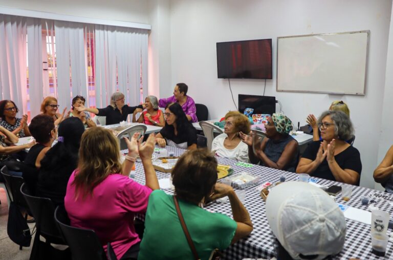 Pessoas participando de uma oficina de jardinagem em um CRAS de Maricá, com plantas e ferramentas.