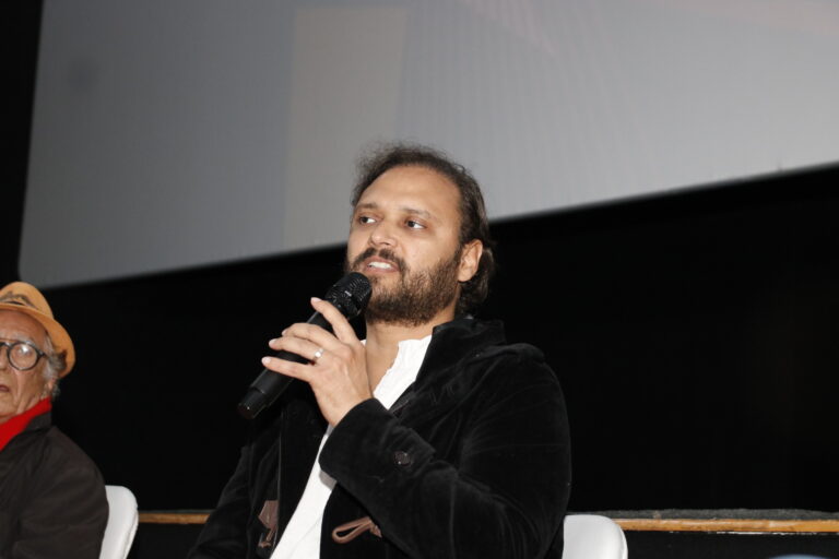 Pessoas assistem a debate em palco durante o Festival de Cinema e Política no Cine Henfil, Maricá.