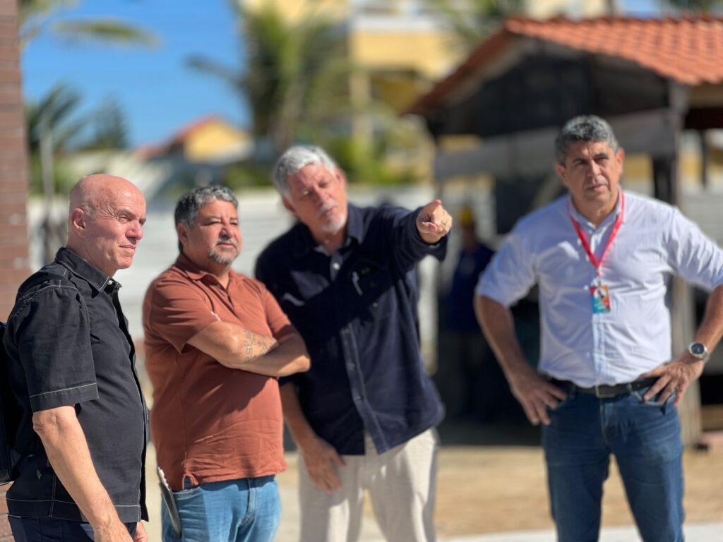 Obras da Praça das Utopias em Cordeirinho, Maricá, com vista para o mar e estruturas em construção.