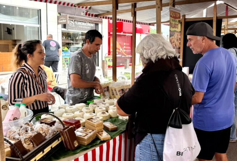 Feira da Agricultura Familiar em Maricá, com barracas de produtos frescos e pessoas comprando em Itaipuaçu.