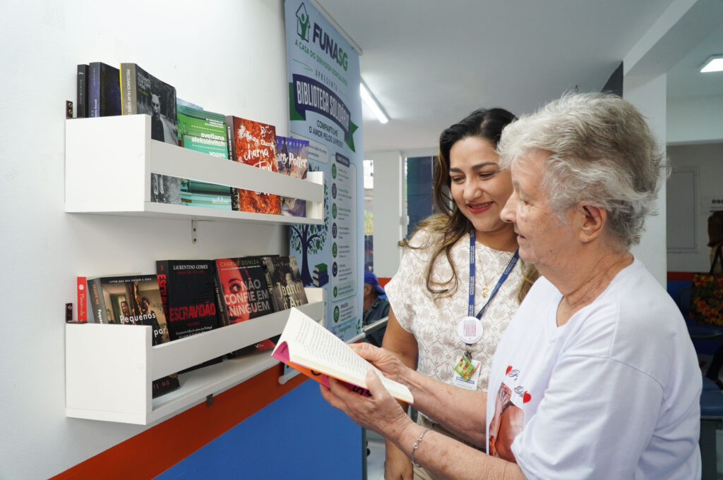 Usuários da Funasg consultam livros na Biblioteca Solidária, em São Gonçalo, visando bem-estar.