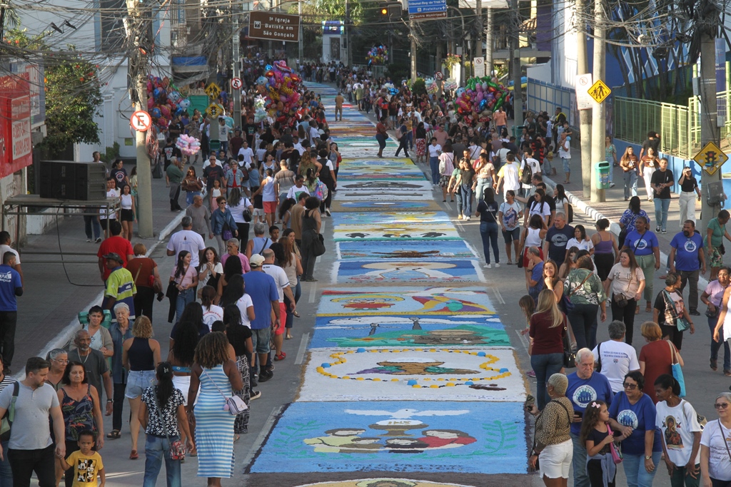 Vista aérea dos tapetes de sal coloridos e fiéis durante a celebração de Corpus Christi em São Gonçalo.