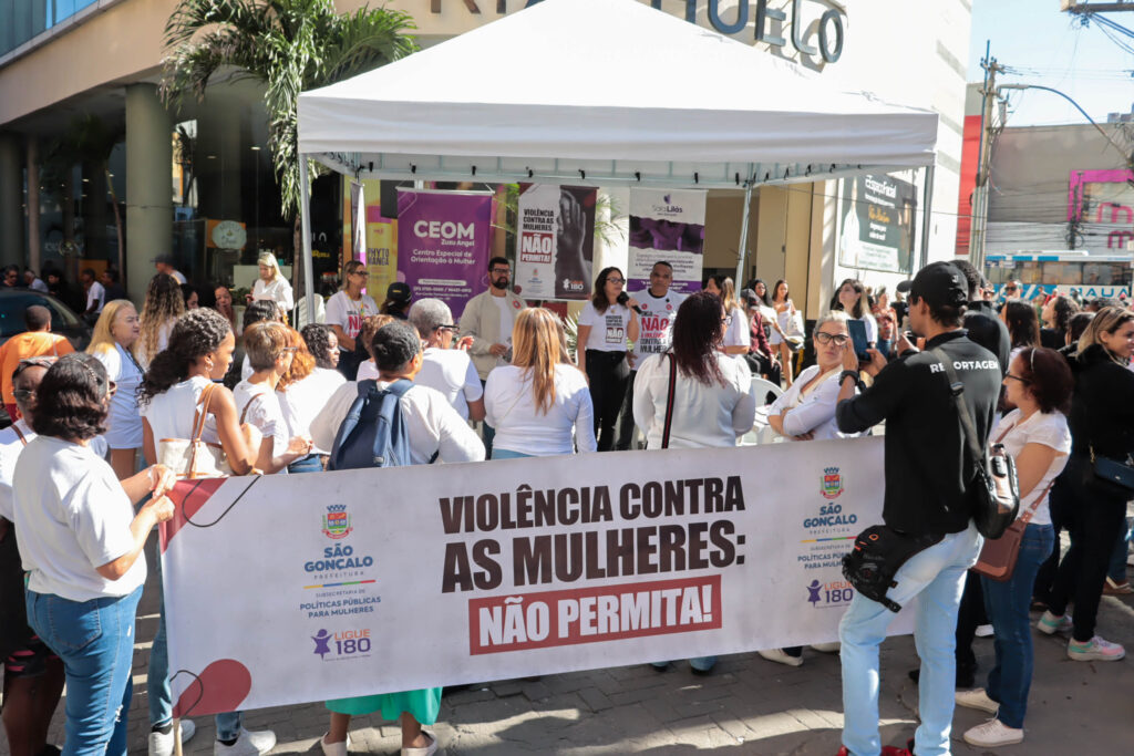 Mulheres em ação de conscientização contra a violência de gênero em São Gonçalo, com faixas de apoio.