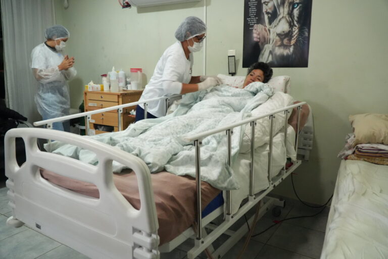 Profissionais de saúde do SAD de São Gonçalo atendem paciente em casa, oferecendo cuidados domiciliares e reabilitação.