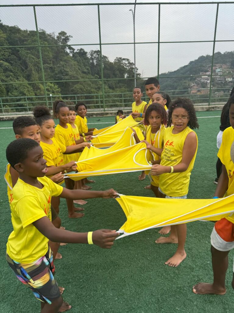 Crianças brincando e praticando esportes em colônia de férias gratuita no Caramujo, Niterói.