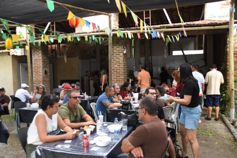 Pessoas em evento ao ar livre com barracas e atividades, celebrando o Curta Itaocaia julina em Maricá.