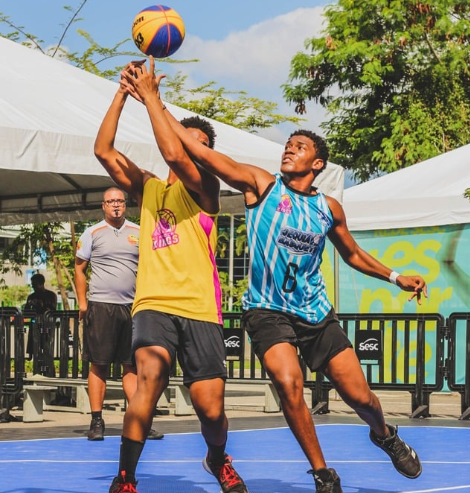 Atletas jogando basquete 3x3 em quadra ao ar livre na Concha Acústica de Niterói, com público ao redor.