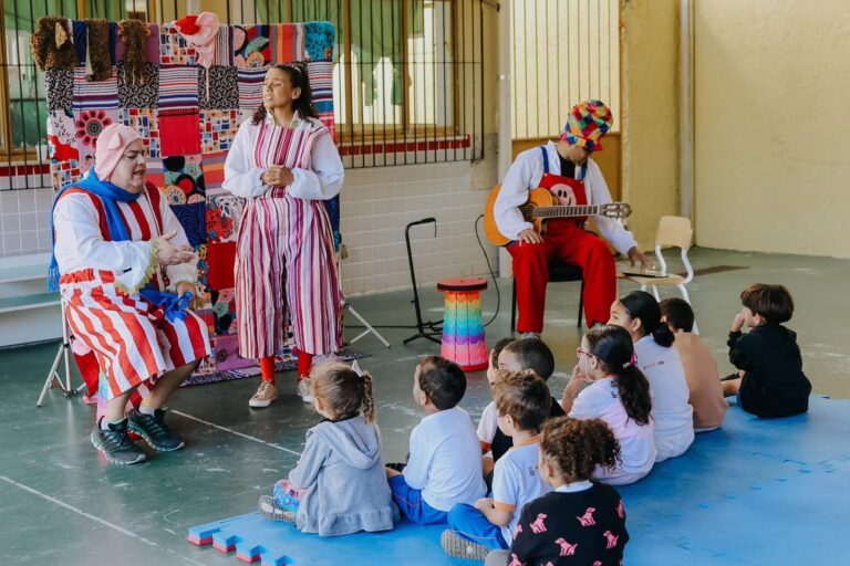 Crianças sorrindo em atividade cultural do programa 'Tô de Férias na Escola' em escola municipal de Niterói.