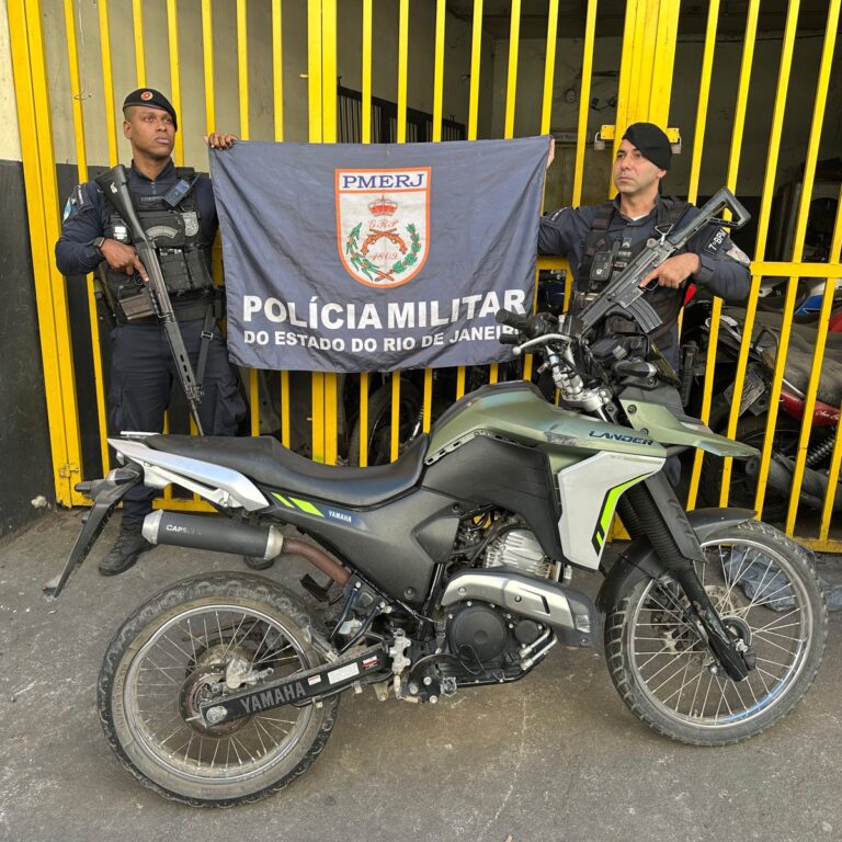 Policiais militares próximos a uma motocicleta recuperada em São Gonçalo. Veículo com registro de roubo.