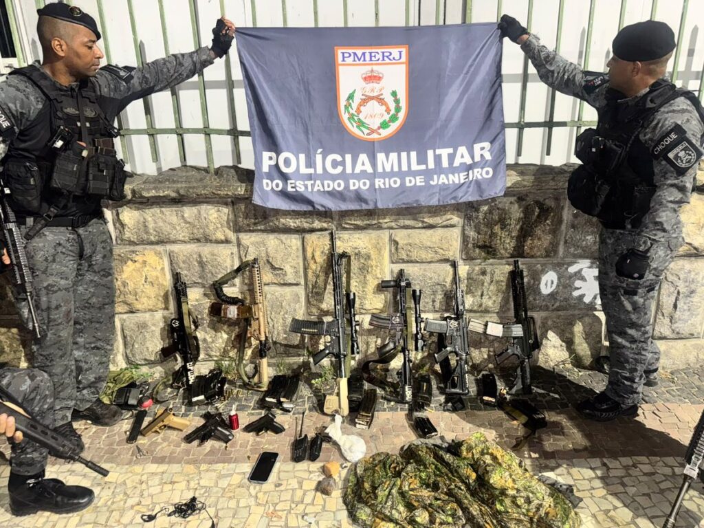 Policial militar do Rio de Janeiro com fuzis apreendidos em operação no estado.