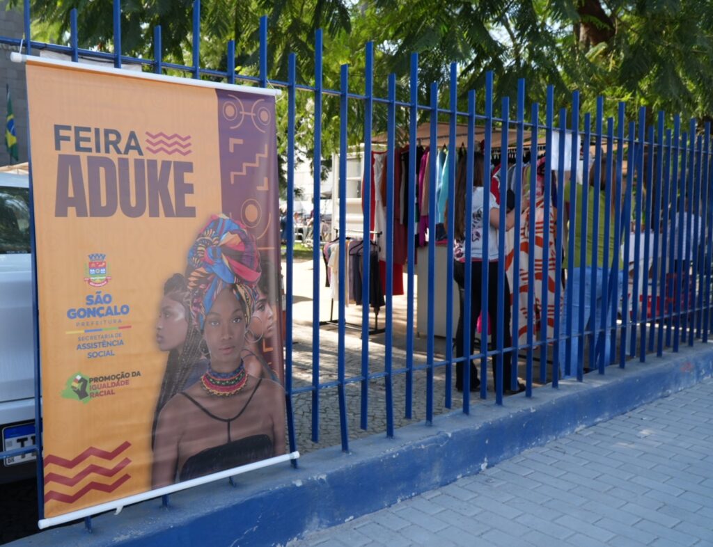 Feira Aduke em São Gonçalo com expositores de produtos afro-brasileiros e público interagindo.