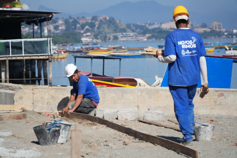 Imagem da orla da Praia das Pedrinhas em São Gonçalo durante obras de revitalização, com calçadas e pilares de pergolados.