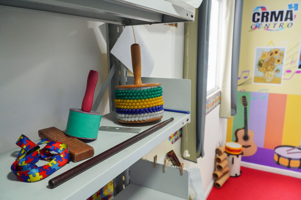 Criança autista em São Gonçalo praticando musicoterapia com instrumentos musicais para desenvolver habilidades.