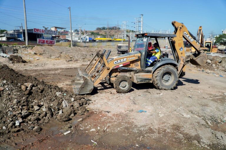 Obras do MUVI em São Gonçalo com máquinas e trabalhadores na Rua Adelaide Lima, Jardim Catarina, construindo ciclovia e calçada.
