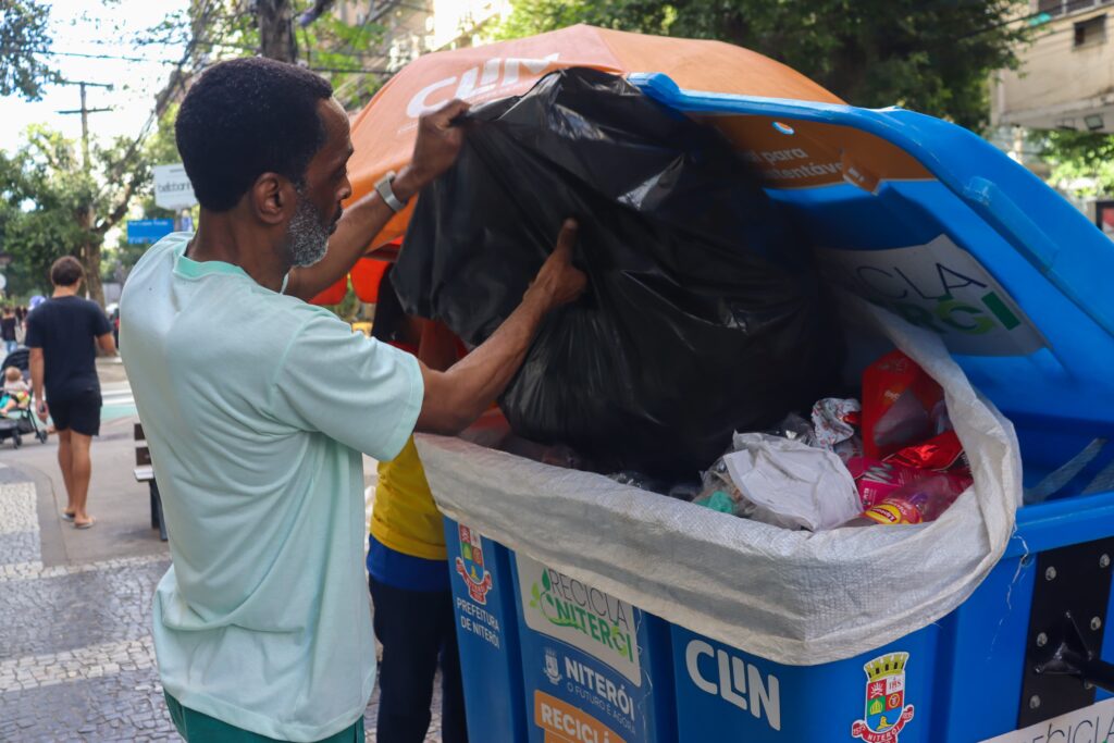 Funcionário da Clin orienta morador sobre descarte de recicláveis em novo ponto do Recicla Niterói.