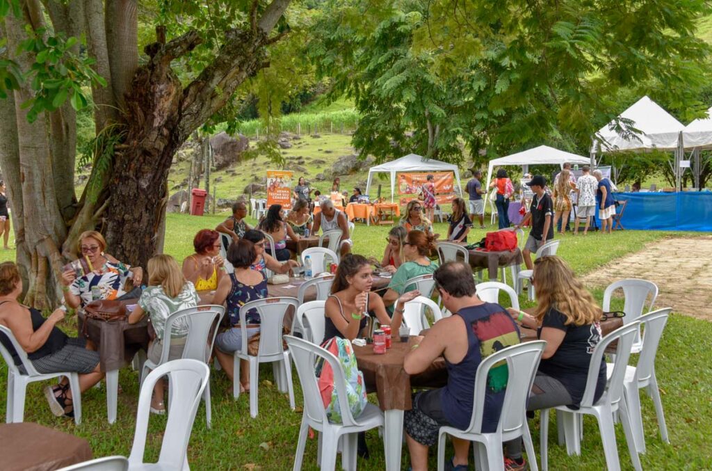 Pessoas participam de evento ao ar livre em Maricá, com barracas e atividades culturais