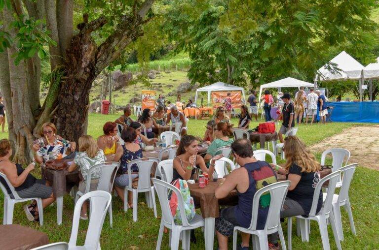 Pessoas participam de evento ao ar livre em Maricá, com barracas e atividades culturais