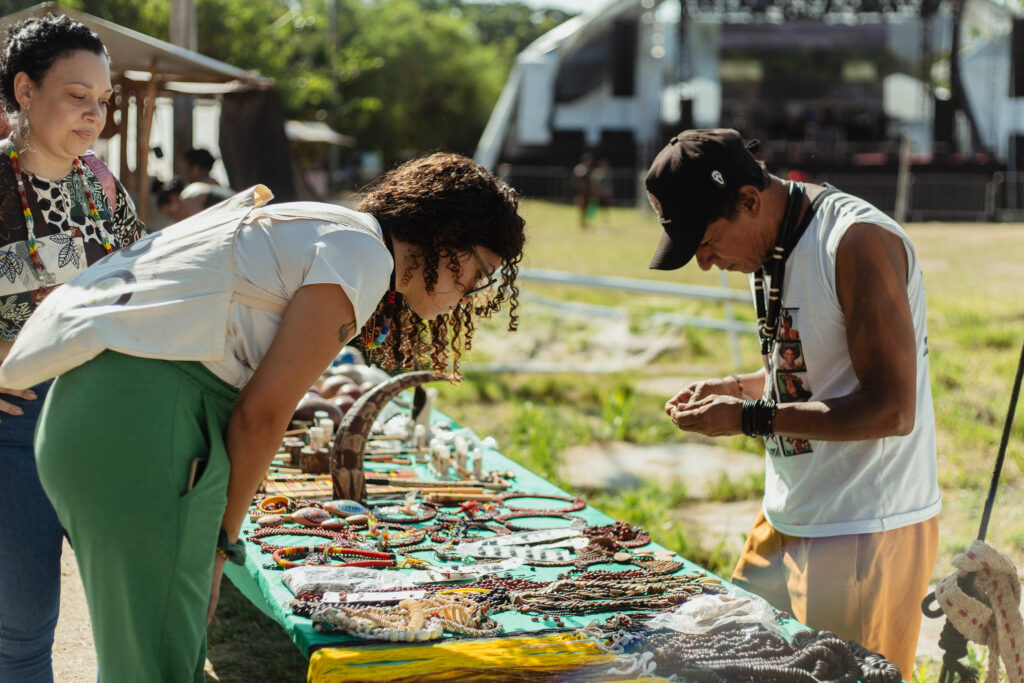 Pessoas participando de evento cultural em Maricá, com palco e público ao fundo