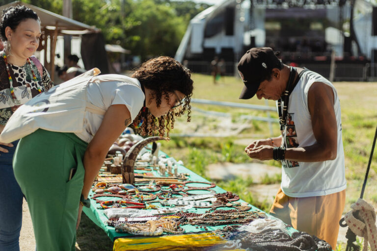 Pessoas participando de evento cultural em Maricá, com palco e público ao fundo