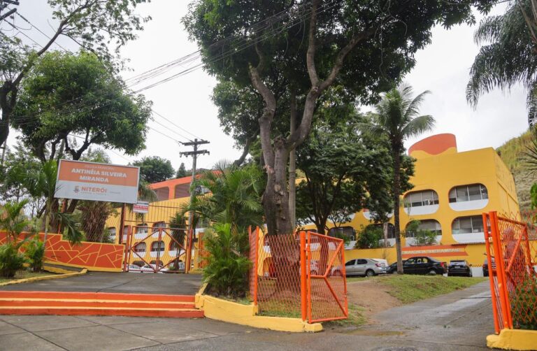Estudantes praticando diversas modalidades esportivas em uma quadra poliesportiva durante aula na escola.