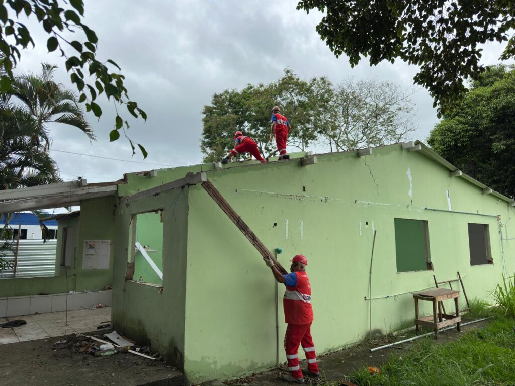 Construção de Unidade de Saúde da Família em Maricá, RJ, com operários e máquinas no canteiro de obras.