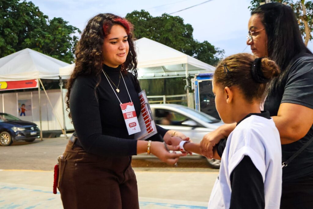 Criança com pulseira de identificação em evento público da Prefeitura de Maricá para segurança infantil.
