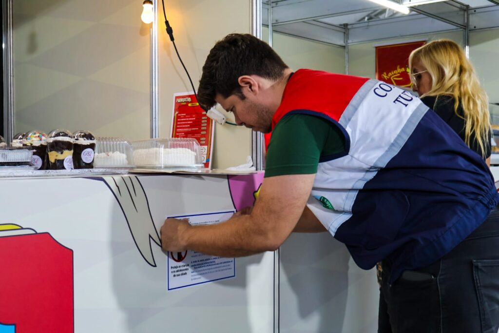 Crianças recebendo pulseiras de identificação em ação de segurança na Festa da Padroeira de Maricá.