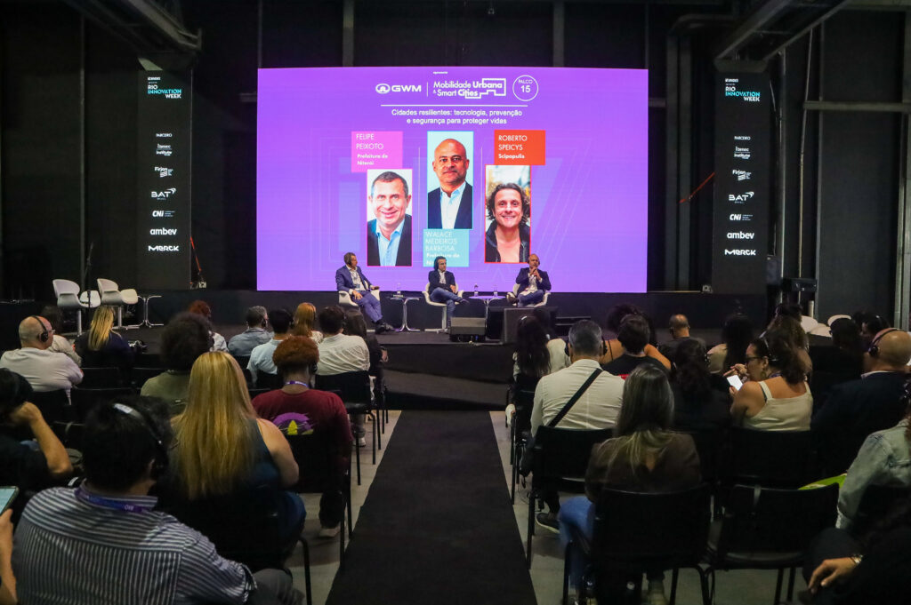 Estande da Prefeitura de Niterói no Rio Innovation Week com pessoas assistindo palestras e interagindo.