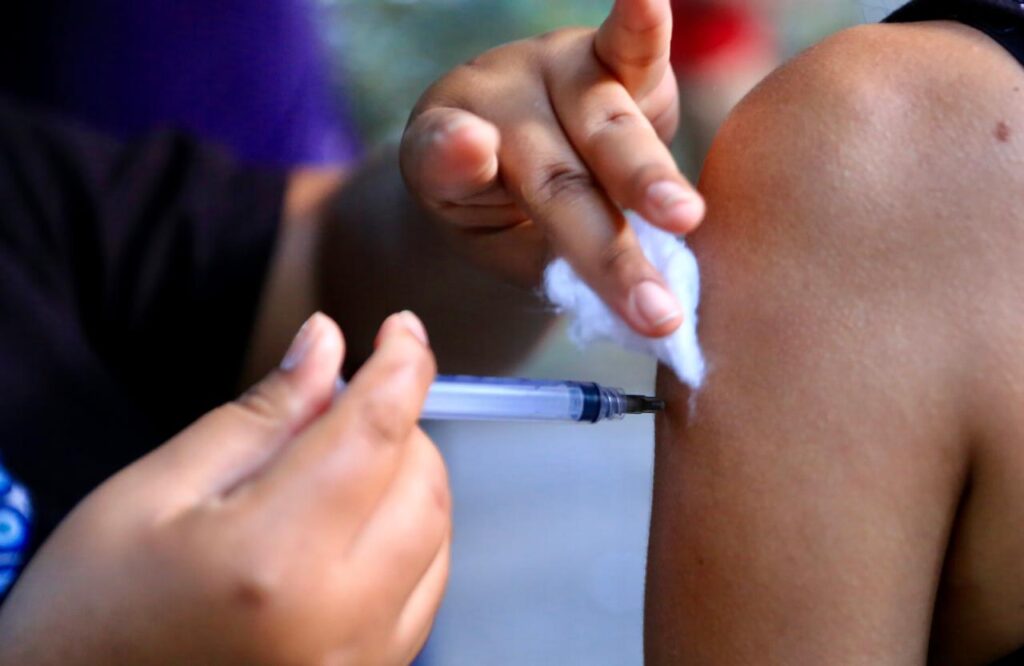 Profissional de saúde aplicando vacina em criança durante campanha de multivacinação em Niterói.