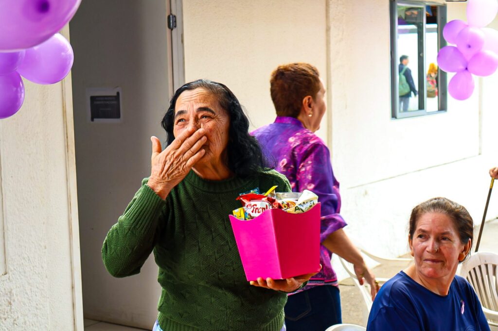 Alunos e professora da oficina de Letramento em Maricá participam de almoço comunitário, interagindo e sorrindo.