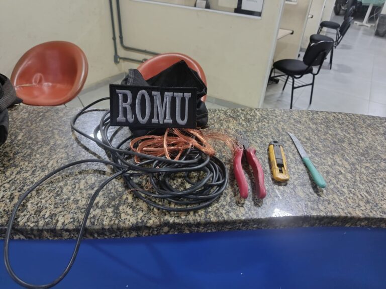 Guardas municipais em patrulhamento em São Gonçalo, com viatura e câmeras de segurança ao fundo.