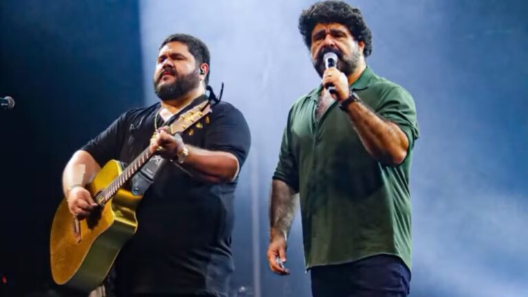 César Menotti e Fabiano cantam no palco da Expo Rural Maricá, com luzes e público ao fundo.