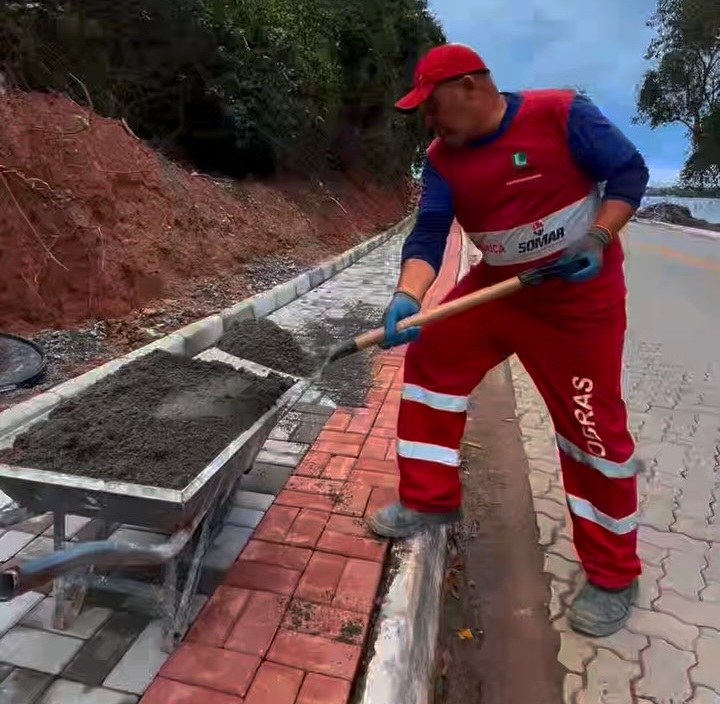 Obras de revitalização de calçadas em Jacaroá, Maricá, com trabalhadores e maquinário em ação.