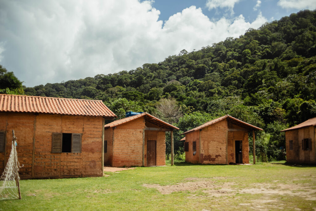 Vista aérea da Aldeia Indígena Céu Azul em Maricá, com casas e vegetação, representando moradia segura.